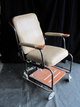 Wheelchair (c) old, brown vinyl w text ‘WARD’